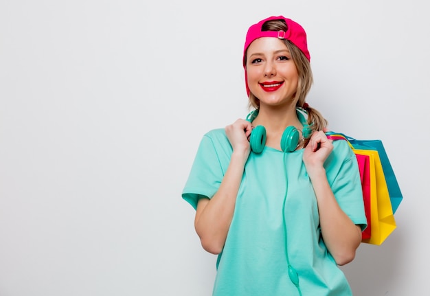 Chica con gorra rosa y camiseta azul con bolsas de la compra.