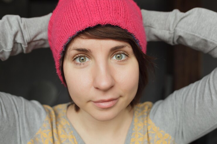 Foto la chica con una gorra rosa mira hacia adelante con las manos detrás de la cabeza.
