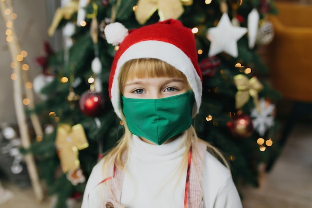 Chica con gorro y máscara de Papá Noel, Navidad, encierro en vacaciones, covid-19, coronavirus.