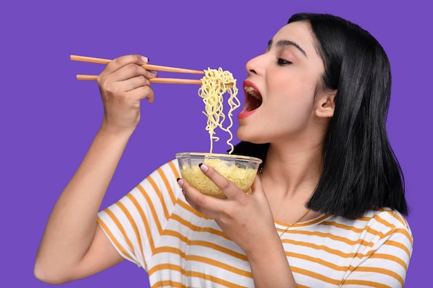 Chica gourmet comiendo fideos sobre fondo morado modelo paquistaní indio