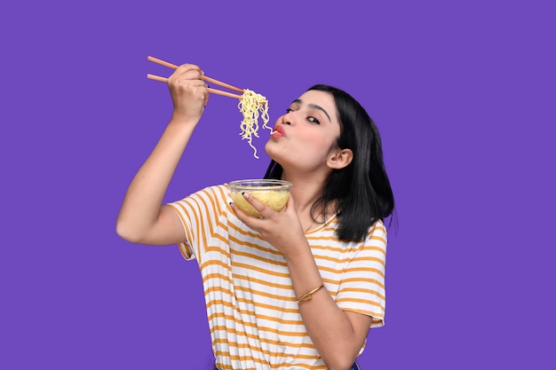 Chica gourmet comiendo fideos sobre fondo morado modelo paquistaní indio