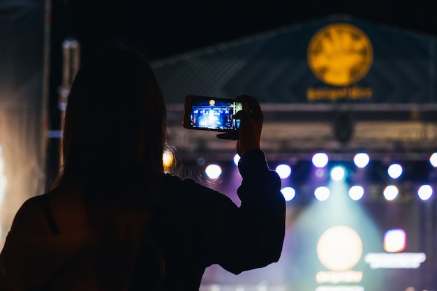 Chica graba un video en un teléfono móvil en un concierto en vivo del músico Basta