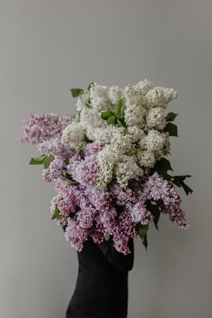 Chica con un gran ramo de lilas sobre un fondo gris