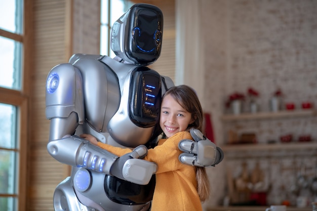 Foto chica y gran robot en la cocina abrazándose