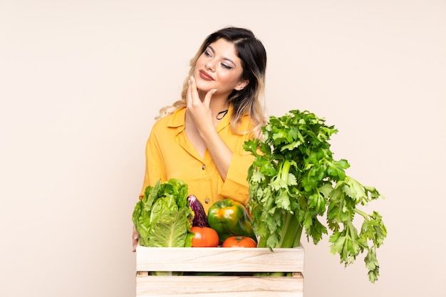 Chica de granjero adolescente con verduras recién cogidas en una caja