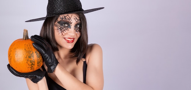 Foto una chica con guantes negros sostiene una calabaza para halloween