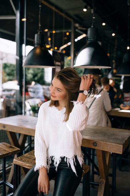 Chica guapa arreglando su cabello en un café