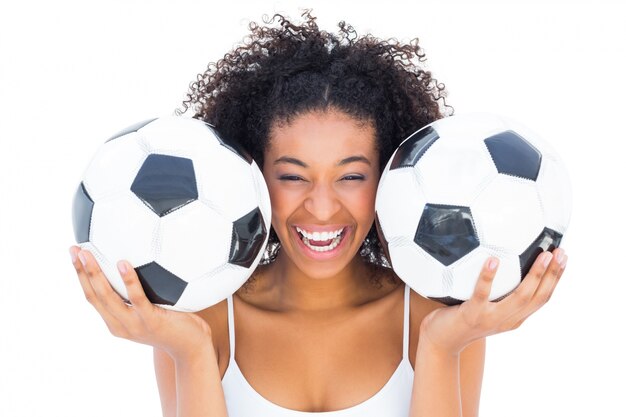 Chica guapa con balones de fútbol y riéndose de la cámara