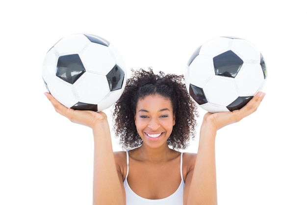 Chica guapa con balones de fútbol y sonriendo a la cámara