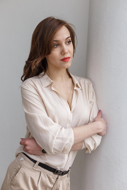 Chica guapa caucásica con el pelo rizado de labios rojos en elegante blusa beige al aire libre