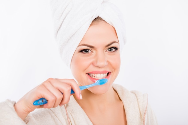 Chica guapa se cepilla los dientes sobre un fondo blanco.