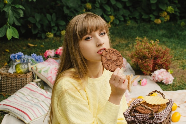 Chica guapa con una cesta de galletas en un picnic