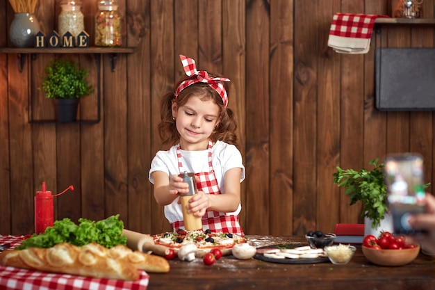 Chica guapa en delantal a cuadros cocinando pizza