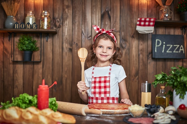 Chica guapa en delantal a cuadros cocinando pizza