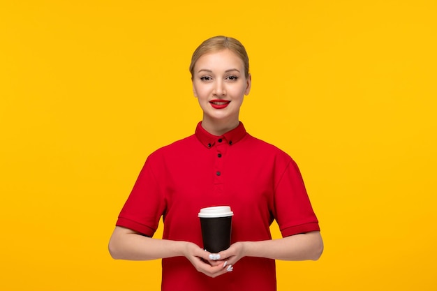 Chica guapa del día de la camisa roja sosteniendo una taza de café en una camisa roja sobre un fondo amarillo