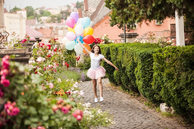 Chica guapa con grandes globos de látex de colores posando en la calle de un casco antiguo