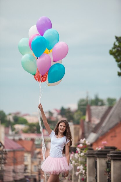 Chica guapa con grandes globos de látex de colores posando en la calle de un casco antiguo