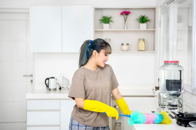 Chica guapa con guantes mientras limpia la cocina