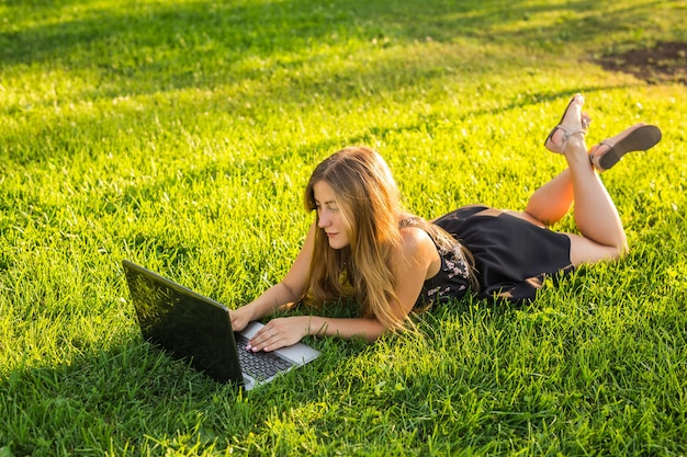 Chica guapa joven con laptop trabajando al aire libre