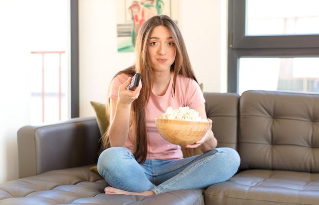 Foto chica guapa joven con palomitas de maíz viendo una película en casa