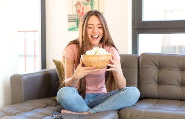 Chica guapa joven con palomitas de maíz viendo una película en casa