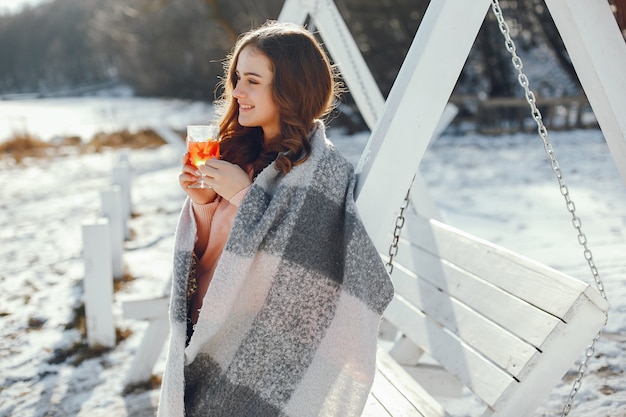 chica guapa joven en el parque de invierno bebiendo mulledwine