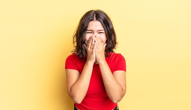 Chica guapa joven que parece feliz, alegre, afortunada y sorprendida cubriendo la boca con ambas manos