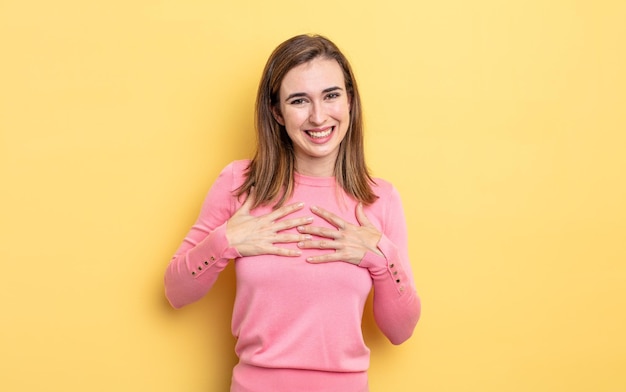 Chica guapa joven que parece feliz, sorprendida, orgullosa y emocionada, apuntando a sí misma