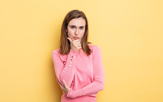 Chica guapa joven que parece seria, confundida, insegura y pensativa, dudando entre opciones o elecciones