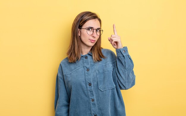 Chica guapa joven que se siente como un genio levantando el dedo con orgullo en el aire después de darse cuenta de una gran idea, diciendo eureka