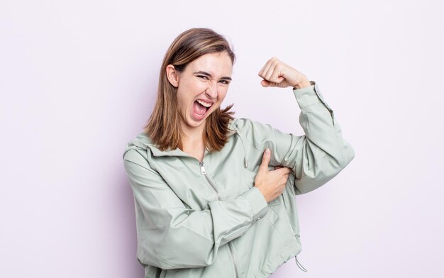 Chica guapa joven que se siente feliz, satisfecha y con un poderoso ajuste flexible y bíceps musculosos que se ven fuertes después del gimnasio