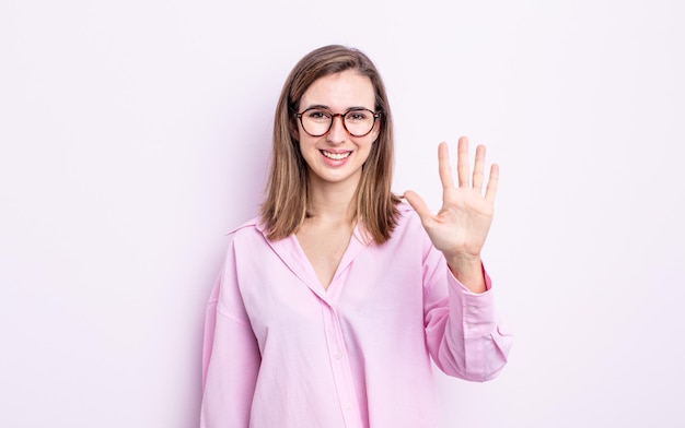 Chica guapa joven sonriendo y luciendo amigable, mostrando el número cinco o quinto con la mano hacia adelante, contando hacia atrás