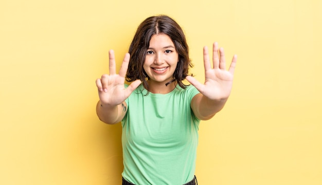 Chica guapa joven sonriendo y luciendo amigable, mostrando el número ocho u octavo con la mano hacia adelante, contando hacia atrás