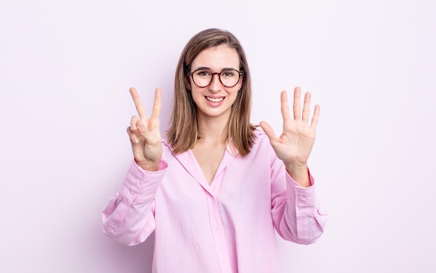 Chica guapa joven sonriendo y luciendo amigable, mostrando el número siete o séptimo con la mano hacia adelante, contando hacia atrás