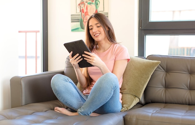 Chica guapa joven usando una tableta en casa