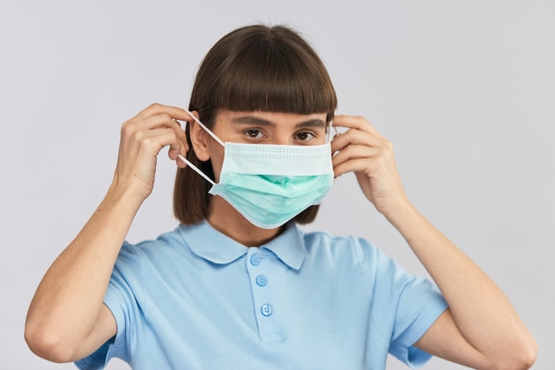 Chica guapa con máscara desechable estéril para proteger la cara contra virus o contaminación del aire