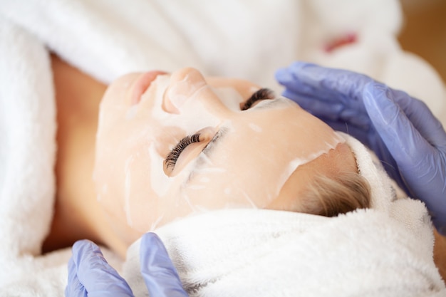 Chica guapa con mascarilla para el cuidado de la cara en casa.