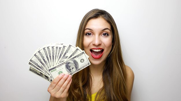 Chica guapa mirando a la cámara con un montón de billetes de dinero