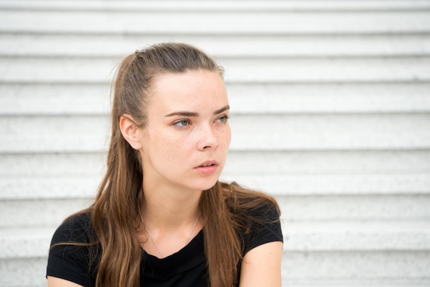 Chica guapa o mujer con el pelo largo sentada en las escaleras de la ciudad