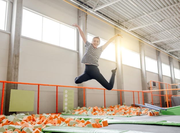 Chica guapa en el parque de trampolines divirtiéndose