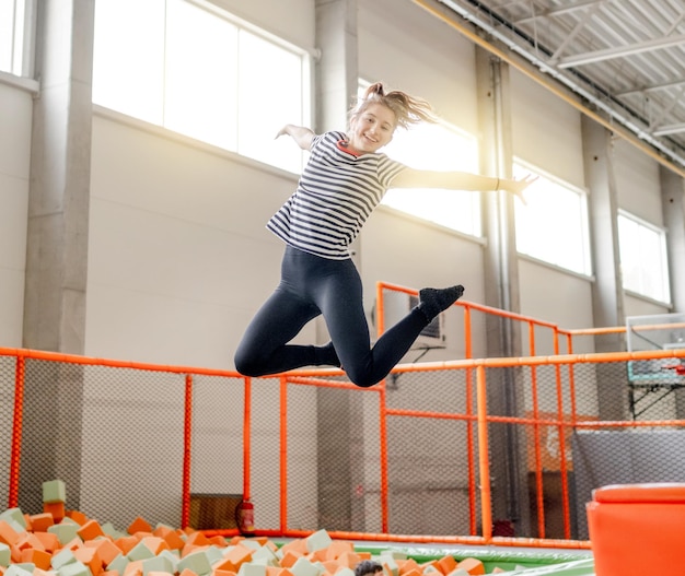 Chica guapa en el parque de trampolines divirtiéndose