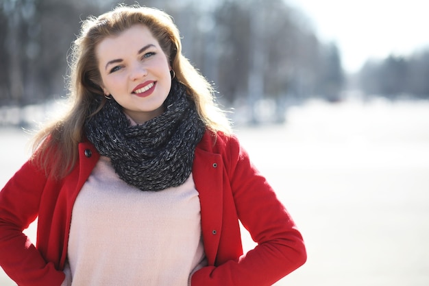 Chica guapa en un paseo con un abrigo rojo en la ciudad