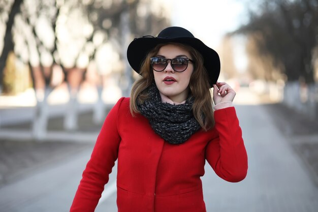 Chica guapa en un paseo en abrigo rojo en la ciudad