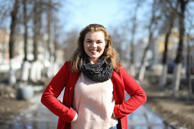 Chica guapa en un paseo con abrigo rojo en la ciudad