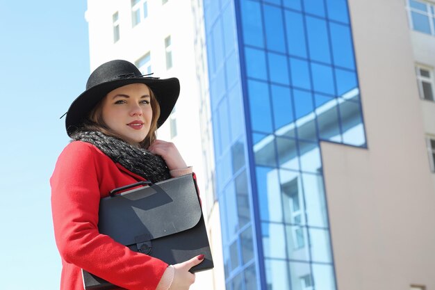 Chica guapa en un paseo con abrigo rojo en la ciudad