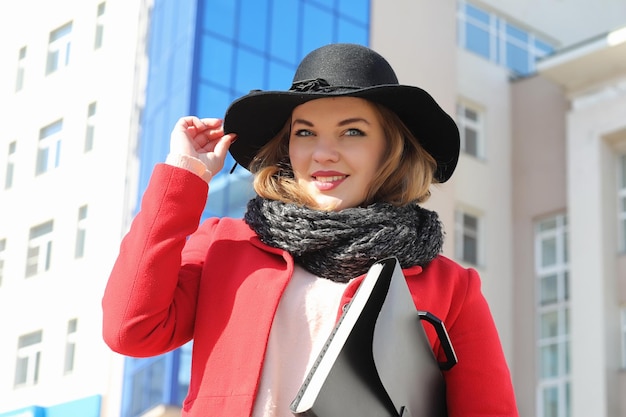 Chica guapa en un paseo en abrigo rojo en la ciudad