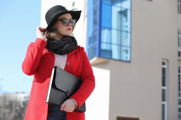 Chica guapa en un paseo en abrigo rojo en la ciudad