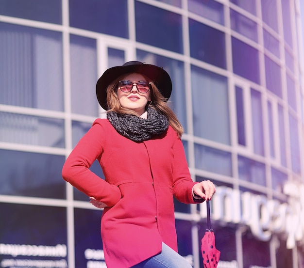 Chica guapa en un paseo en abrigo rojo en la ciudad