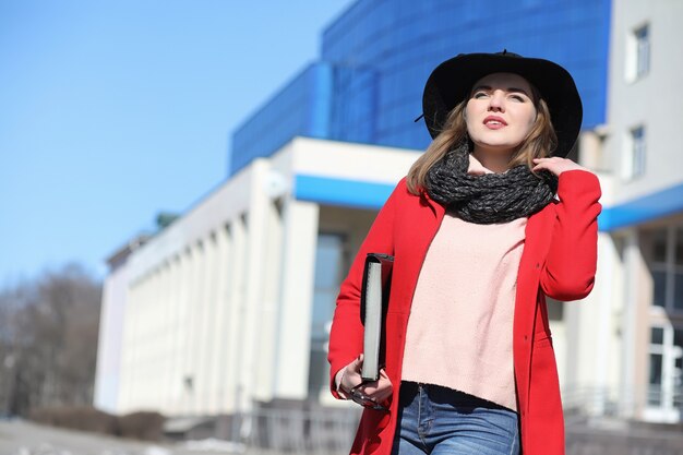 Chica guapa en un paseo en abrigo rojo en la ciudad