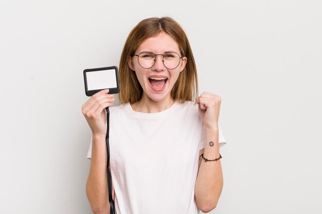 Chica guapa pelirroja sintiéndose sorprendida, riendo y celebrando el éxito del concepto de identificación de pase vip